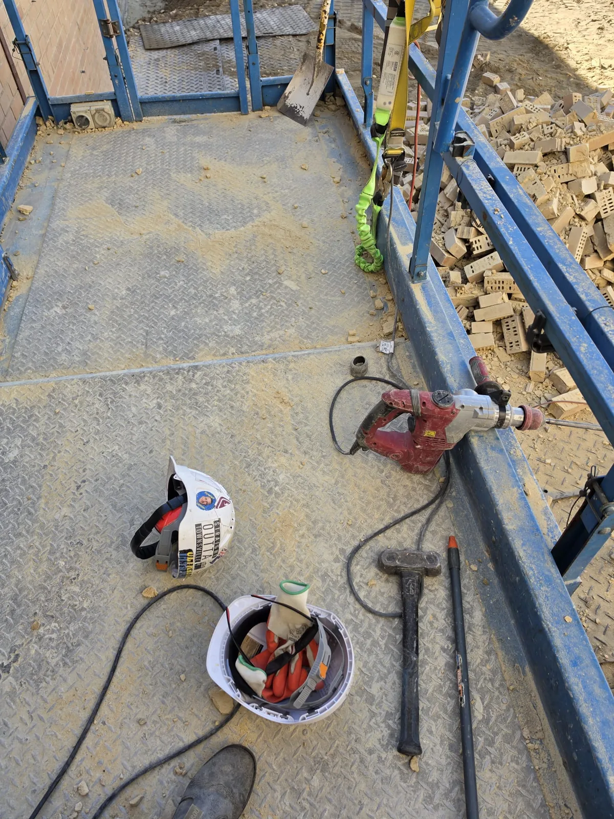 Hard hats, rotary hammer and hand tools laid out on a scaffold platform at the start of a Perth job