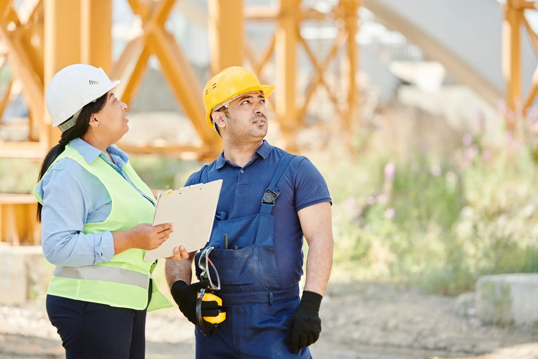 Construction workers and a site supervisor in hard hats and hi-vis reviewing site plans