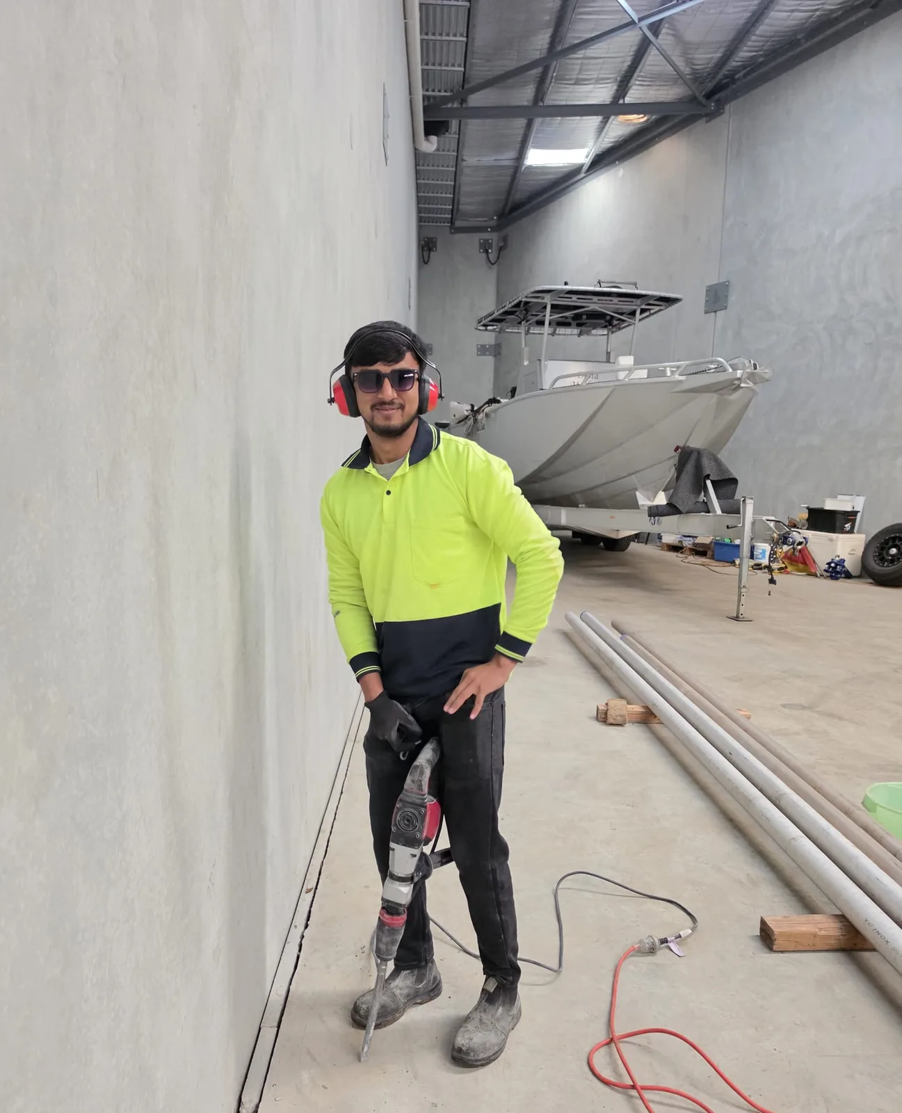 UZI Contracting worker in hi-vis using a jackhammer to cut a concrete slab inside a Perth warehouse