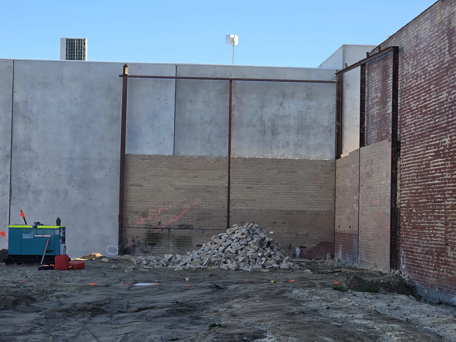 Partially demolished brick wall with rubble stacked for removal on a Perth commercial demolition site