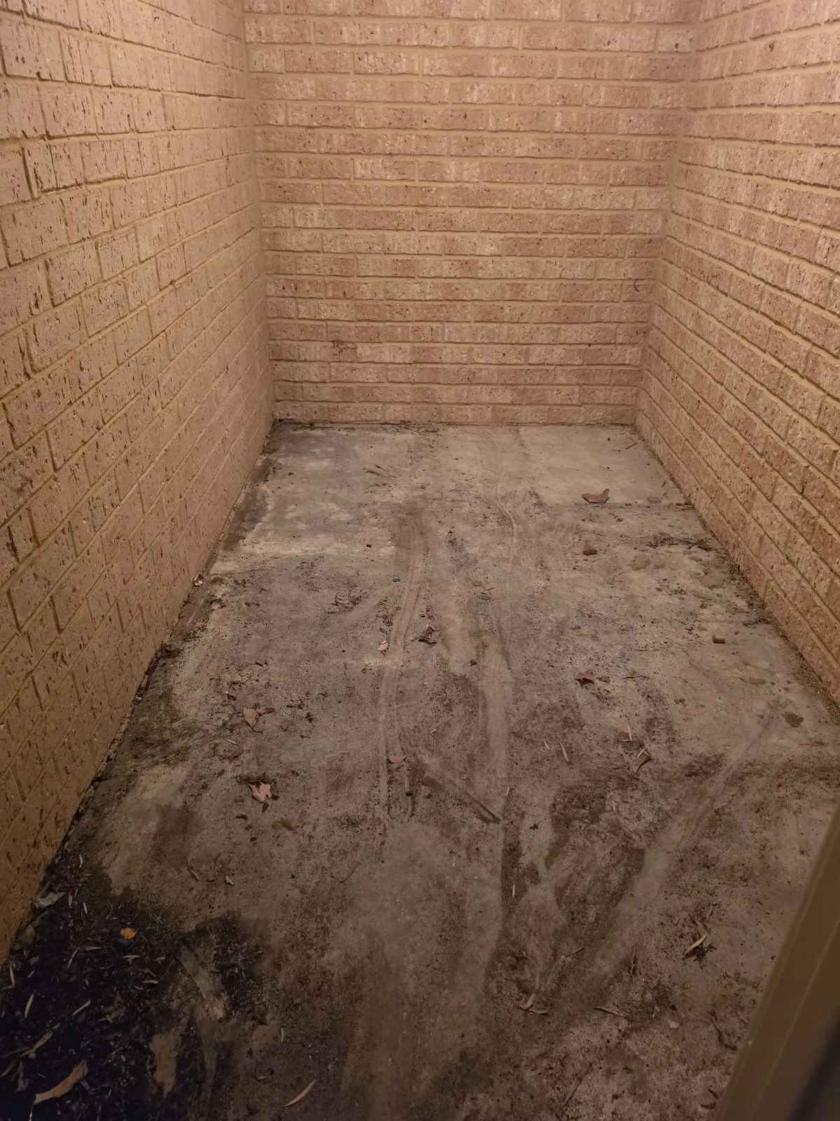 Brick bin enclosure cleared and swept back to bare concrete after a UZI Contracting site clean-up